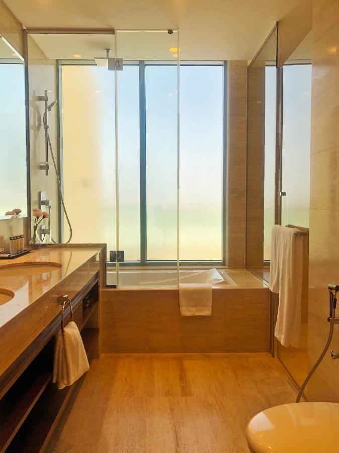 Grand Swiss-Belhotel Waterfront Seef Sanabis Esterno foto The photo features a modern bathroom with a clean and stylish design. It includes a double sink vanity with a wooden countertop and a large mirror. A shower area is visible with a glass wall, allowing for an open feel. There is a bathtub next to a wi