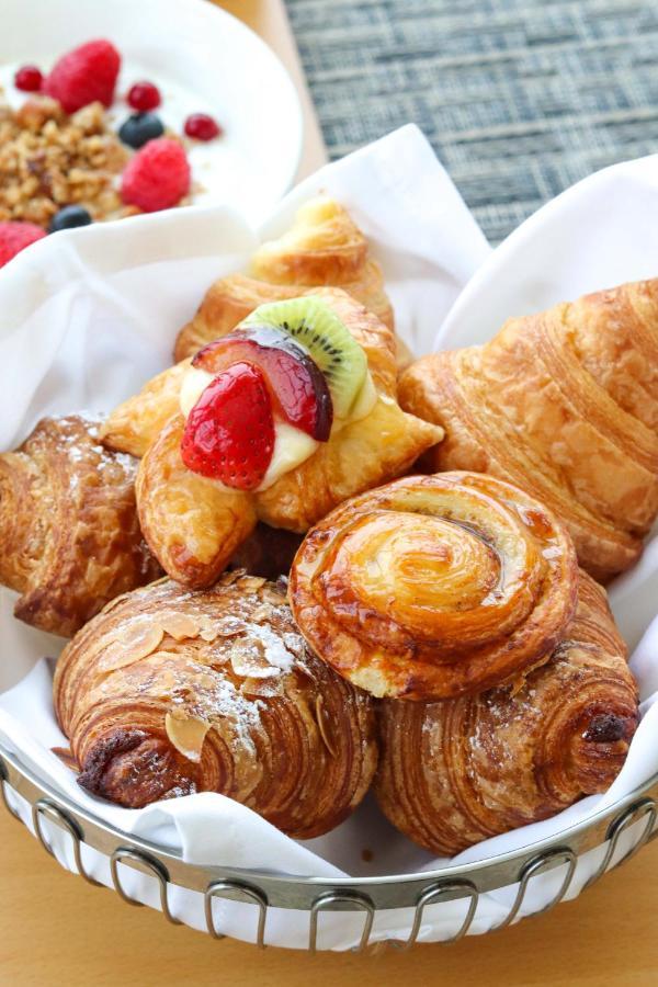 Grand Swiss-Belhotel Waterfront Seef Sanabis Esterno foto The photo showcases a variety of delicious pastries arranged on a white plate. There are croissants, possibly a fruit-filled pastry topped with sliced strawberries and kiwi, and a buttery, spiral-shaped pastry. Each item has a golden-brown color, ind